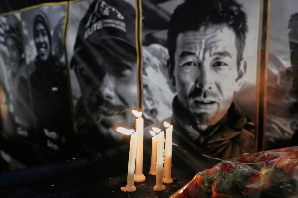 Candles burn next to pictures of climbers who lost their lives on Broad Peak during a candlelight vigil in their memory, in Islamabad, Pakistan, Tuesday, Aug. 11, 2026. (AP Photo/Anjum Naveed)