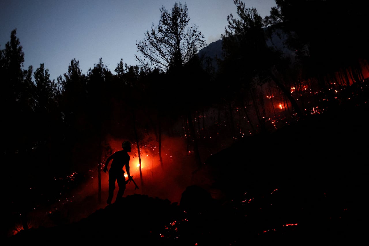 A man's silhouette is seen against a red fire.