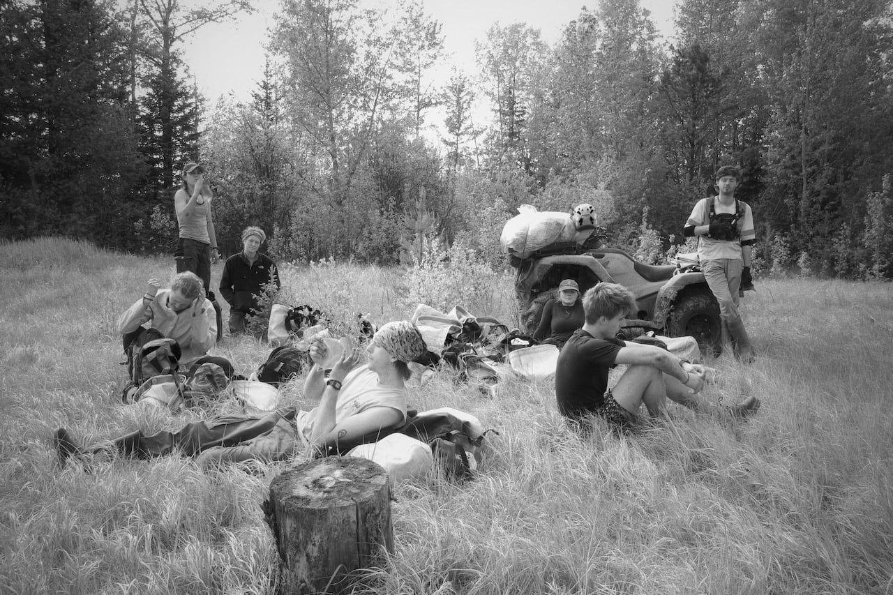 A group of people sit in the grass and appear to be taking a break.