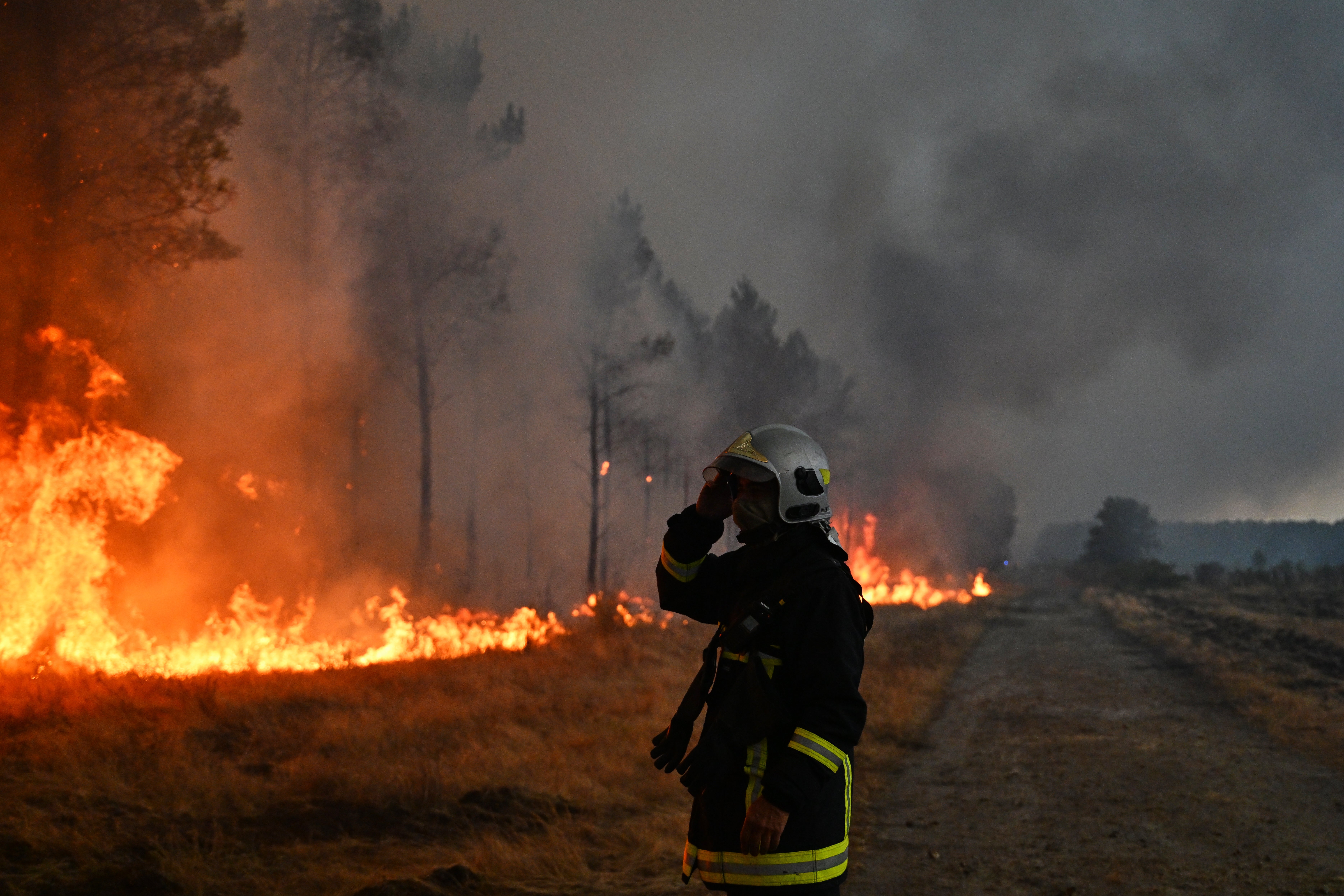 A firefighter watches trees burning as a wildfire rages near Marcheprime, outside, Bordeaux, France