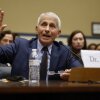 Dr. Anthony Fauci is seated at a table with a microphone and a water bottle in front of him.