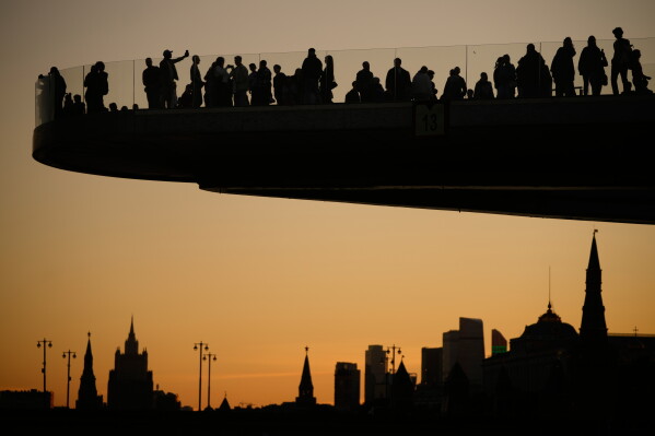 People are silhouetted as they enjoy the view from the Floating Bridge in Zaryadye park, backdropped by the Kremlin, during sunset, in Moscow, Wednesday, Aug. 19, 2026. (AP Photo/Pavel Bednyakov)