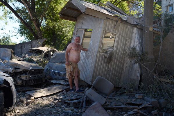 Parking security guard Oleksandr Hnatiuk, 57, smokes a cigarette in front of the booth where he was injured during an overnight Russian missile and drone attack, in Kyiv, Ukraine, Thursday, Aug. 20, 2026. (AP Photo/Francisco Seco)