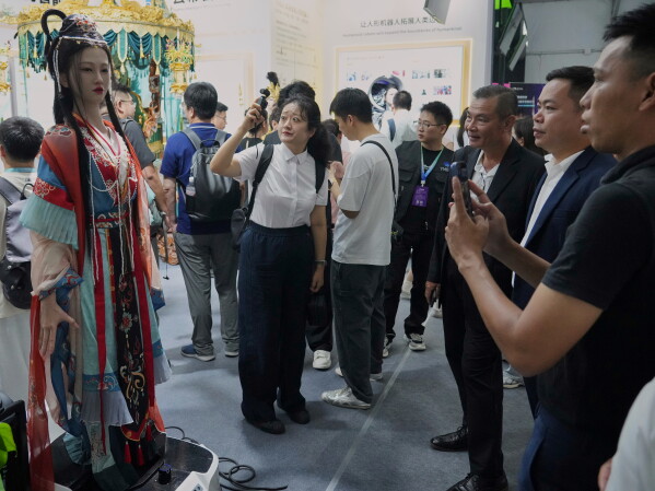 Visitors look at a humanoid robot wearing a traditional dress during the World Robot Conference in Beijing, Thursday, Aug. 20, 2026. (AP Photo/Achmad Ibrahim)