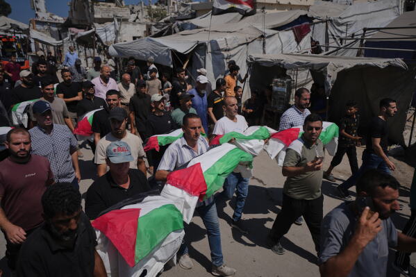 Mourners carry the flag-draped bodies of Palestinians, killed in Israeli strikes during the war with Hamas, whose remains were recently recovered from the rubble in Gaza City, Thursday, Aug. 20, 2026. (AP Photo/Jehad Alshrafi)