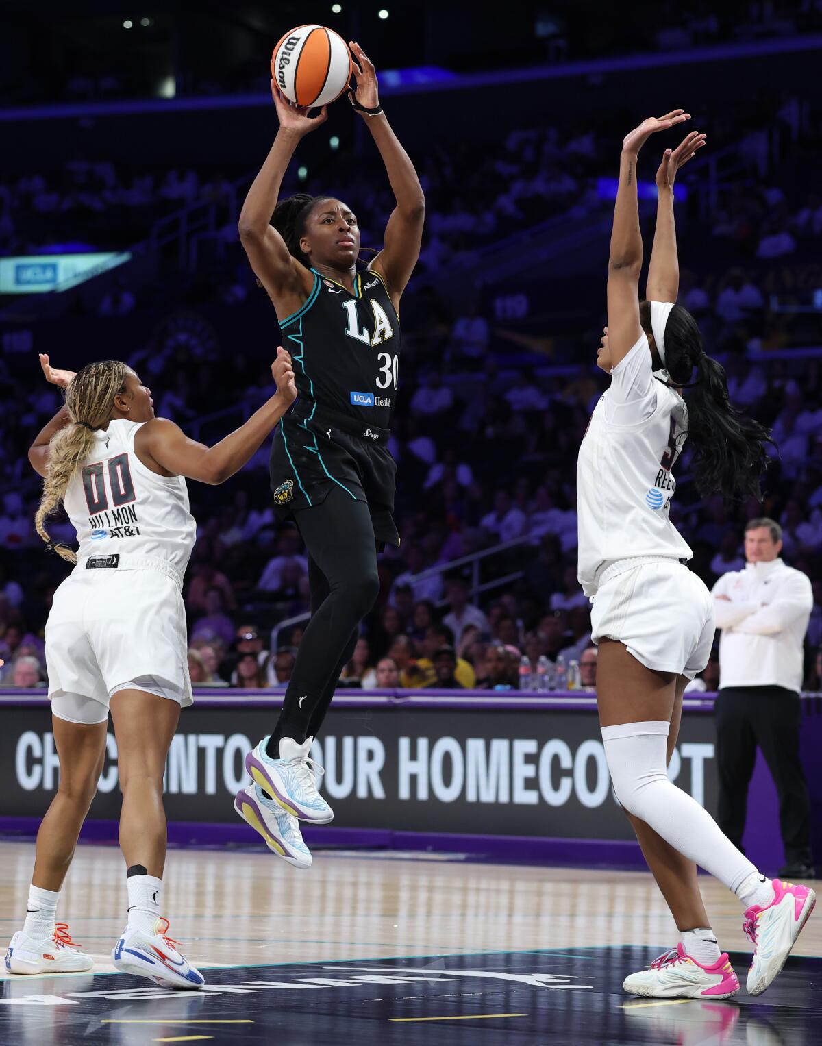 The Sparks' Nneka Ogwumike passes the ball under pressure from the Dream's Naz Hillmon and Angel Reese.