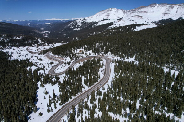 A road winds through the snow-covered Rocky Mountains at Hoosier Pass on April 18, 2022, near Blue River, Colo. (AP Photo/Brittany Peterson, File)