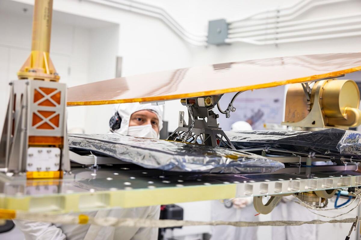 Scientists work on a space vehicle in a clean room.