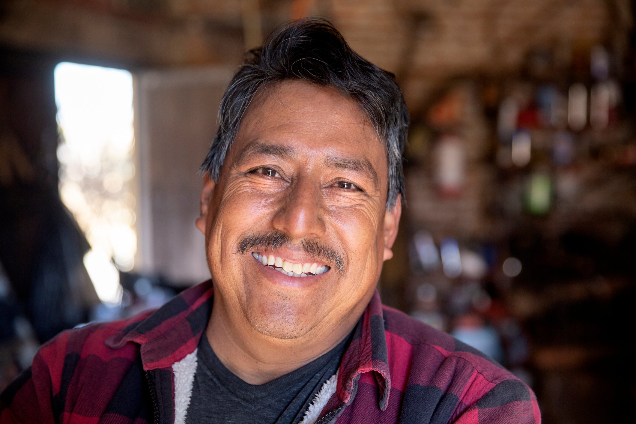 Someone in a flannel shirt is shown in close-up, smiling.