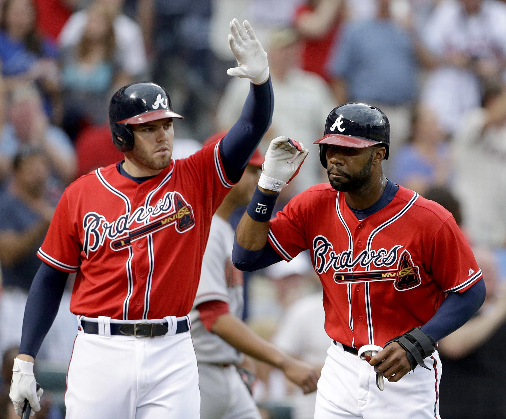 Atlanta Braves' Jason Heyward, right, high-fives teammate Freddie Freeman after scoring off a single by Justin Upton in 2013.