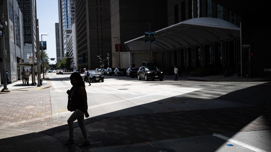 A woman walks in the shade in downtown Houston, Texas, on July 30, 2026, during a regional heat wave.