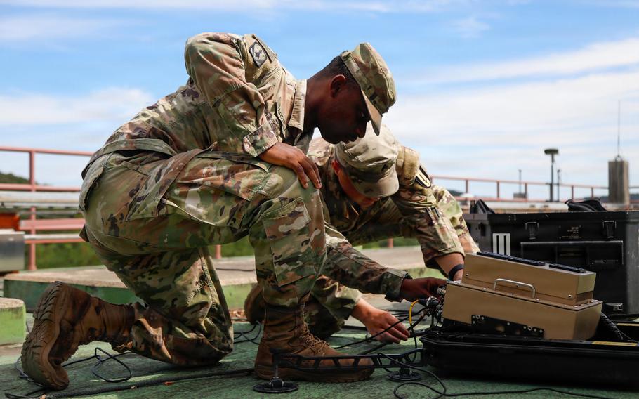 Soldiers work on signal equipment during a training exercise.