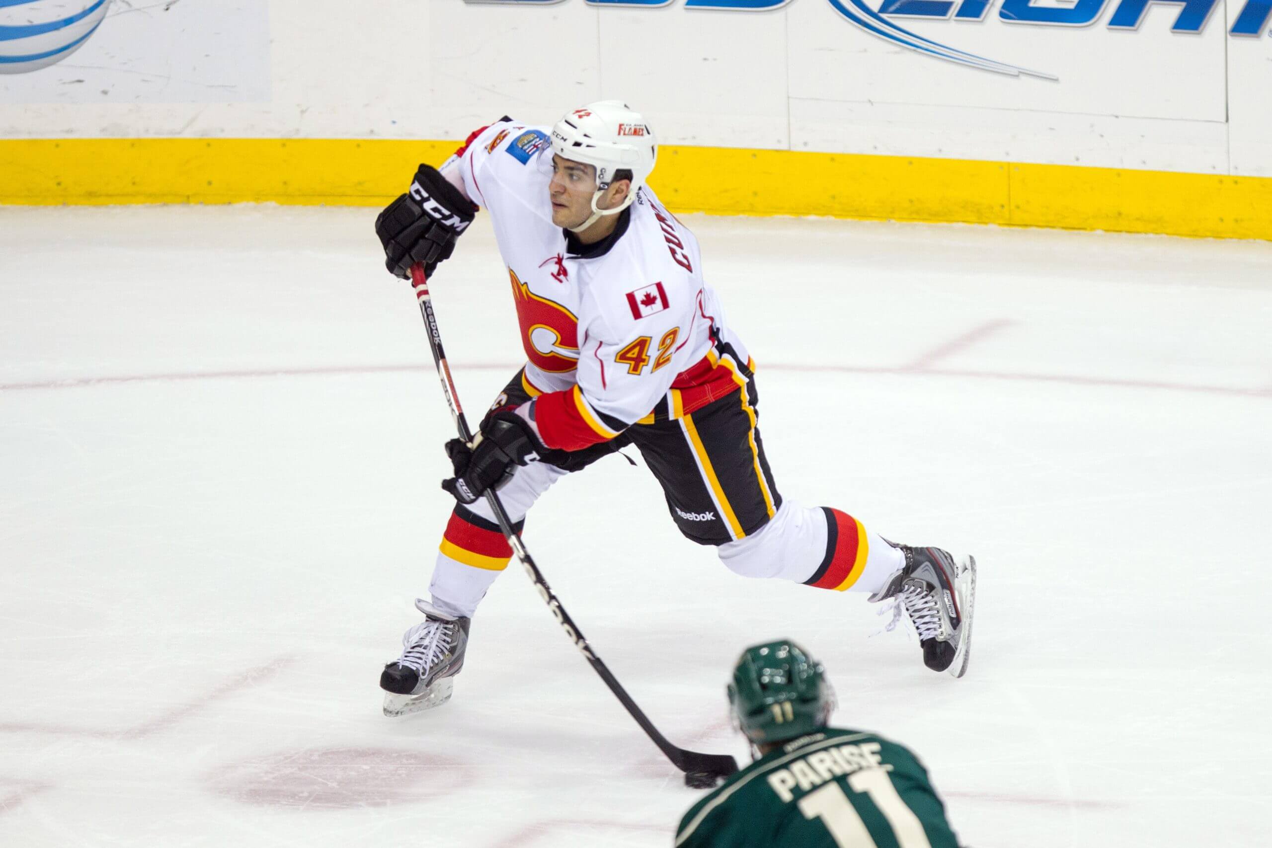 Calgary's Mark Cundari takes a shot, with Wild winger Zach Parise visible at the bottom of the frame.