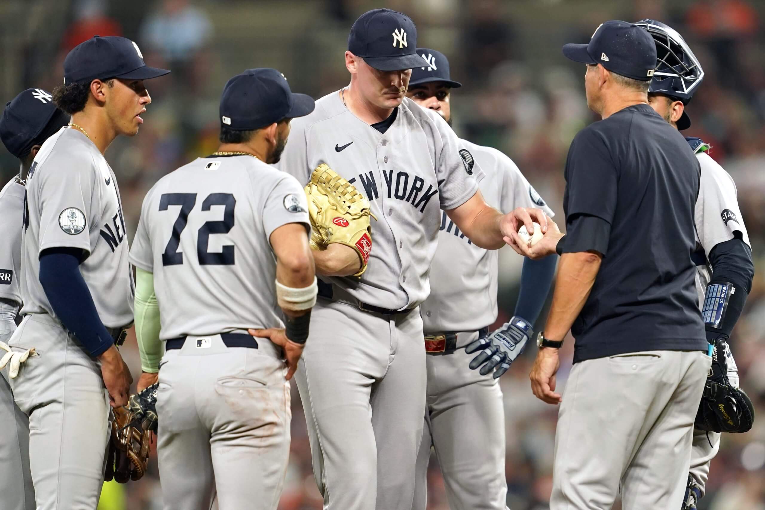 Brent Headrick, surrounded by New York Yankees teammates at the pitcher's mound, hands the ball over to manager Aaron Boone at the end of a two-out relief appearance in in a game against the Baltimore Orioles.