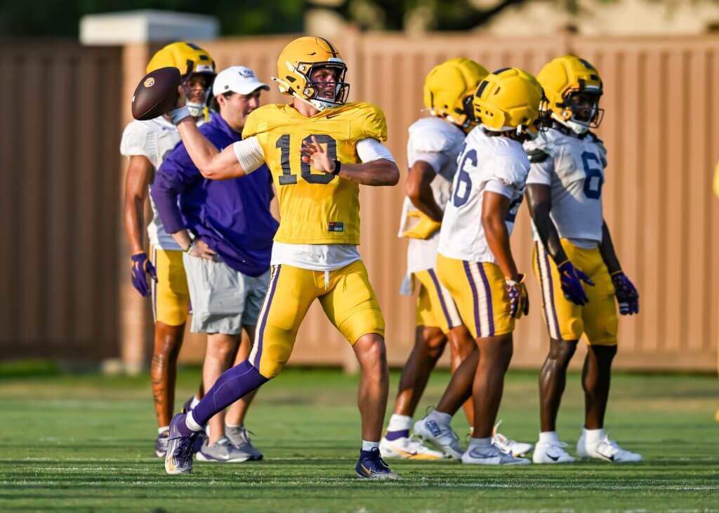 Sam Leavitt winds up to throw a pass with LSU teammates in the background wearing practice jerseys