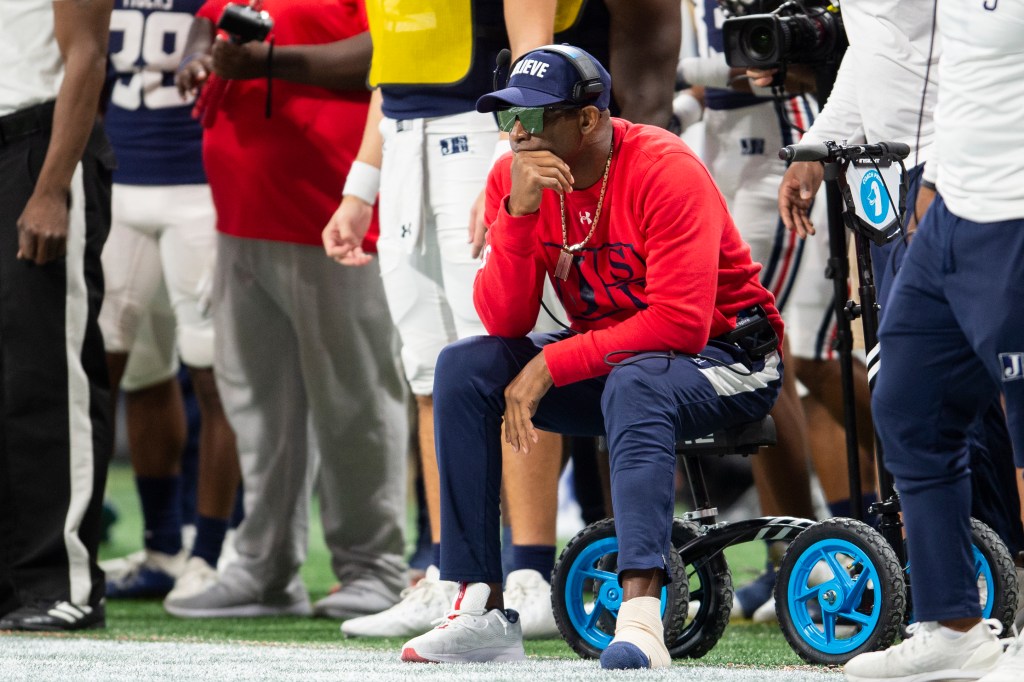 Deion Sanders on a knee scooter on the sidelines of a Jackson State football game.