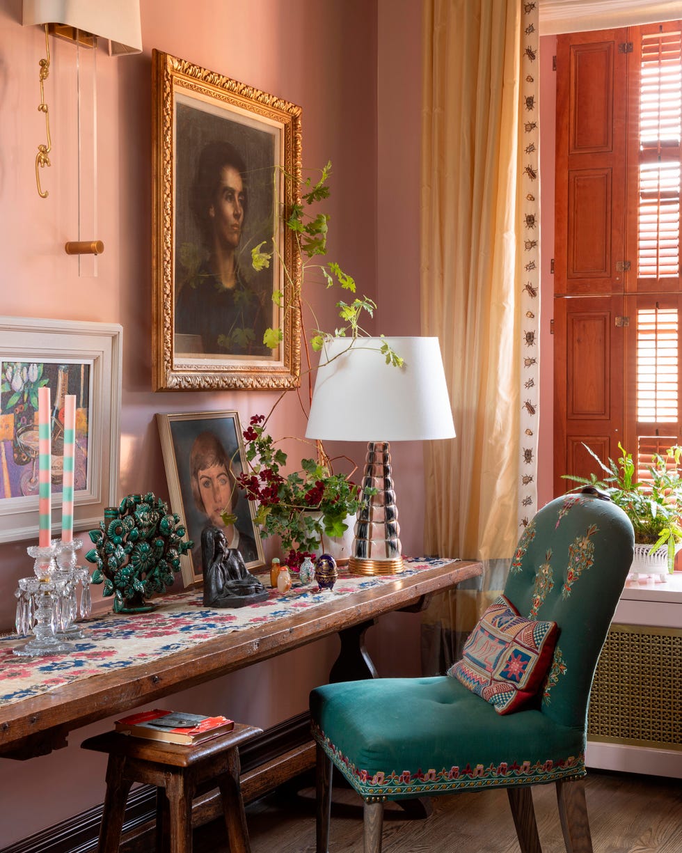 Cozy interior featuring a green chair, decorative table with art, plants, and warm lighting.