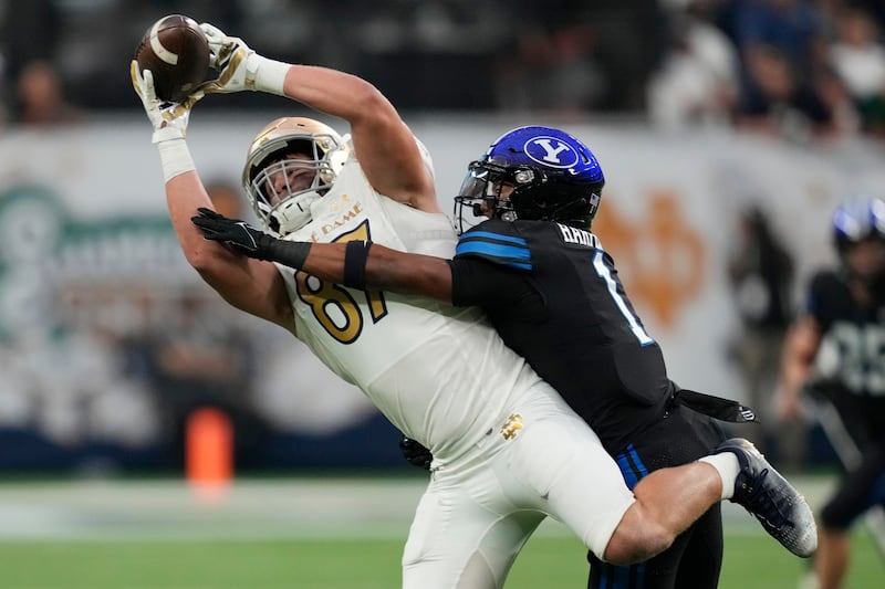 Notre Dame tight end Michael Mayer (87) makes a catch over BYU defensive back Micah Harper (1) during the first half of an NCAA college football game Saturday, Oct. 8, 2022, in Las Vegas. (AP Photo/John Locher)