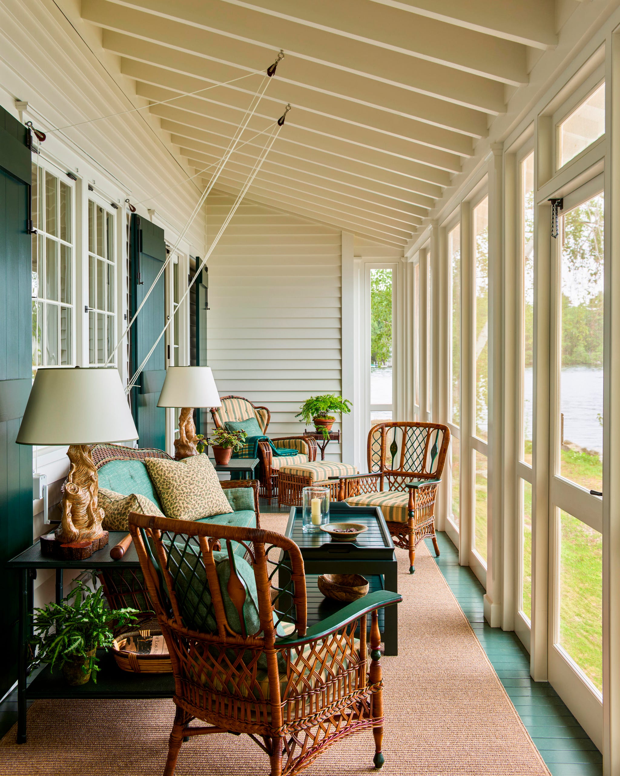 Cozy porch with wicker furniture, lamps, and a view of the lake
