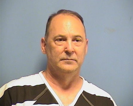 Man in mugshot, wearing white and black stipred shirt.