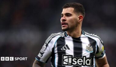 Bruno Guimaraes is looking on in a black and white Newcastle shirt