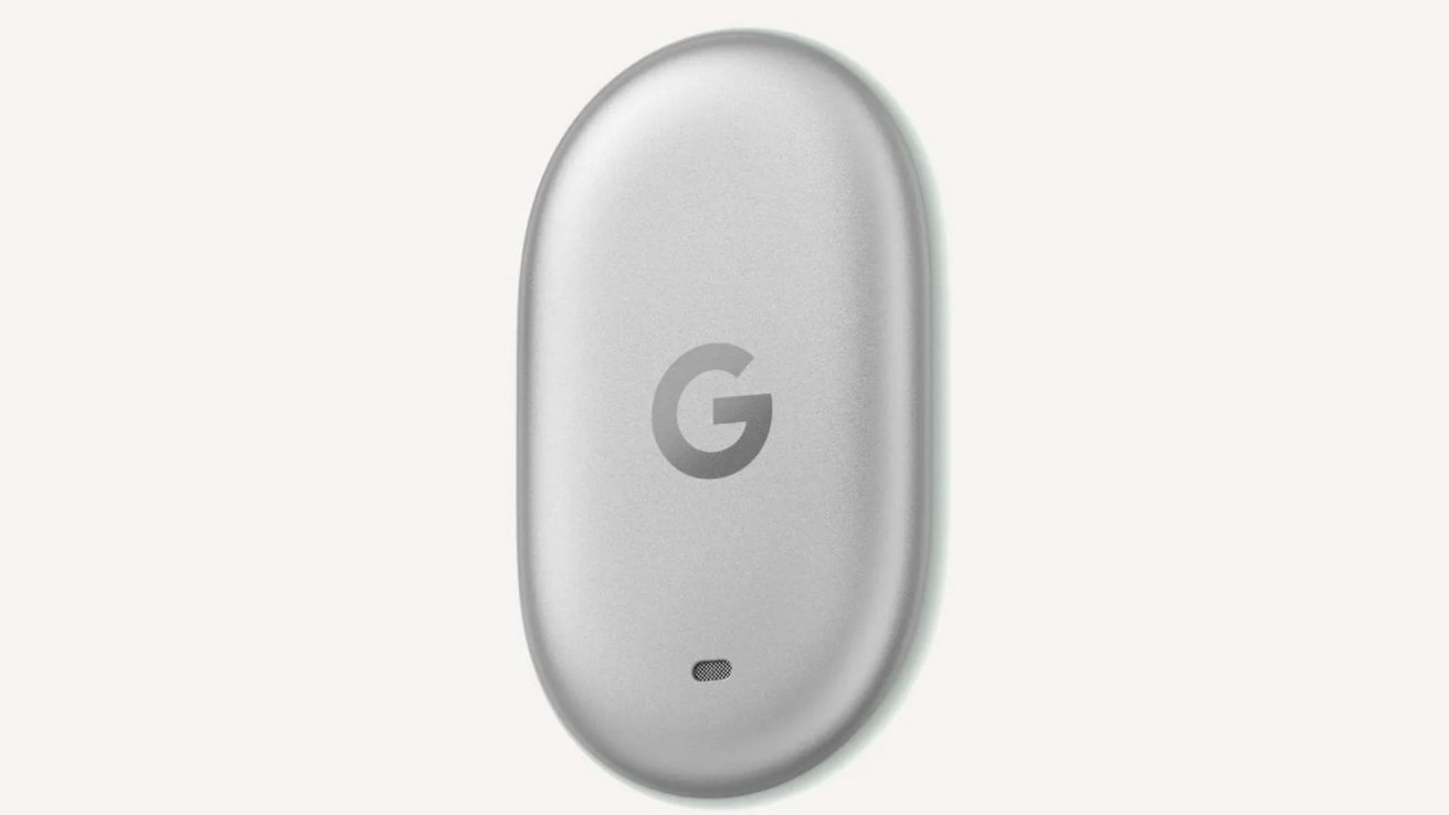 Small, oval, light gray Google device with a subtle G logo centered on the front and a tiny indicator light near the bottom, shown against a plain white background