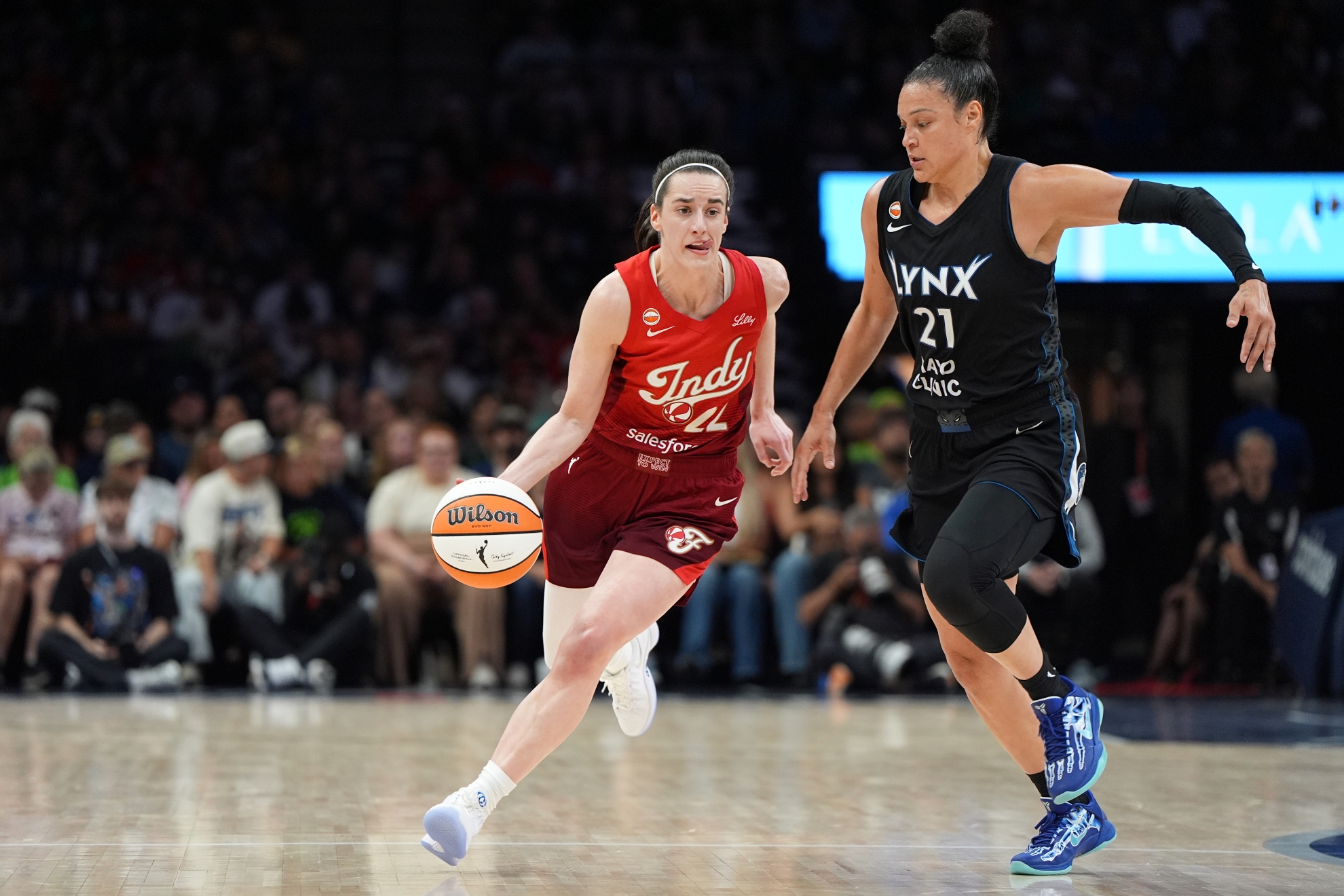 Indiana Fever guard Caitlin Clark, left, dribbles downcourt as Minnesota Lynx guard Kayla McBride (21) defends
