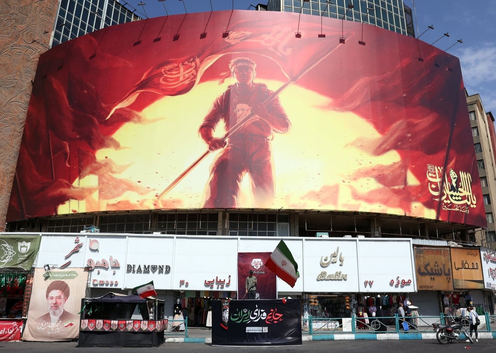 An Iranian man waves the national flag in front of a large political hoarding at Valiasr Square in Tehran on Saturday. Photo: EPA