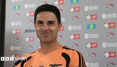 Mikel Arteta stifles a laugh while sitting at a press conference