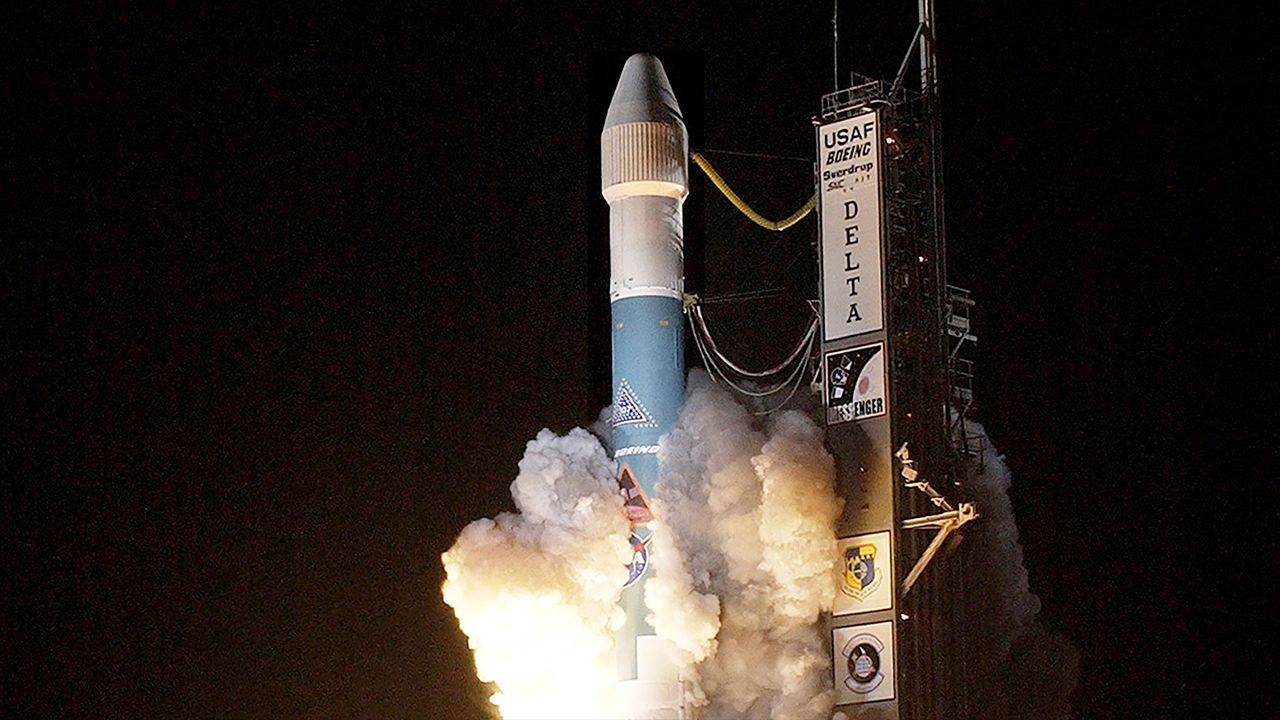 a blue and white rocket lifts off into the night sky