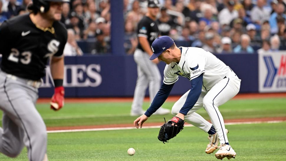Chicago White Sox's Andrew Benintendi, left, runs to first base on a fielding error by Tampa Bay Rays pitcher Griffin Jax, right, during the first inning of a baseball game Sunday, Aug. 2, 2026, in St. Petersburg, Fla. (AP Photo/Jason Behnken)