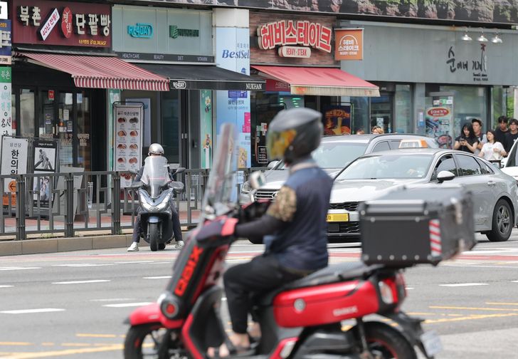 A food delivery worker rides a motorcycle through Seoul, July 8. Yonhap