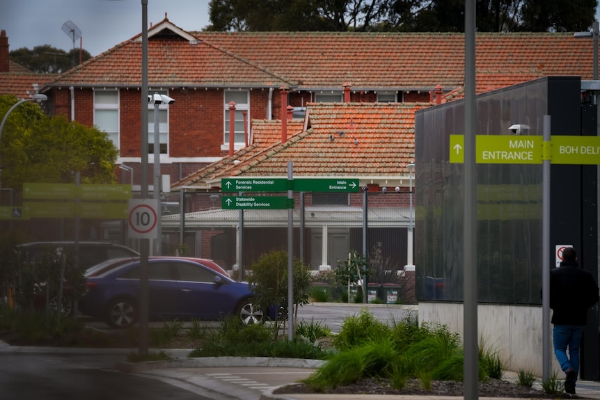 A street shot of a red bricked building in the background and car park in front
