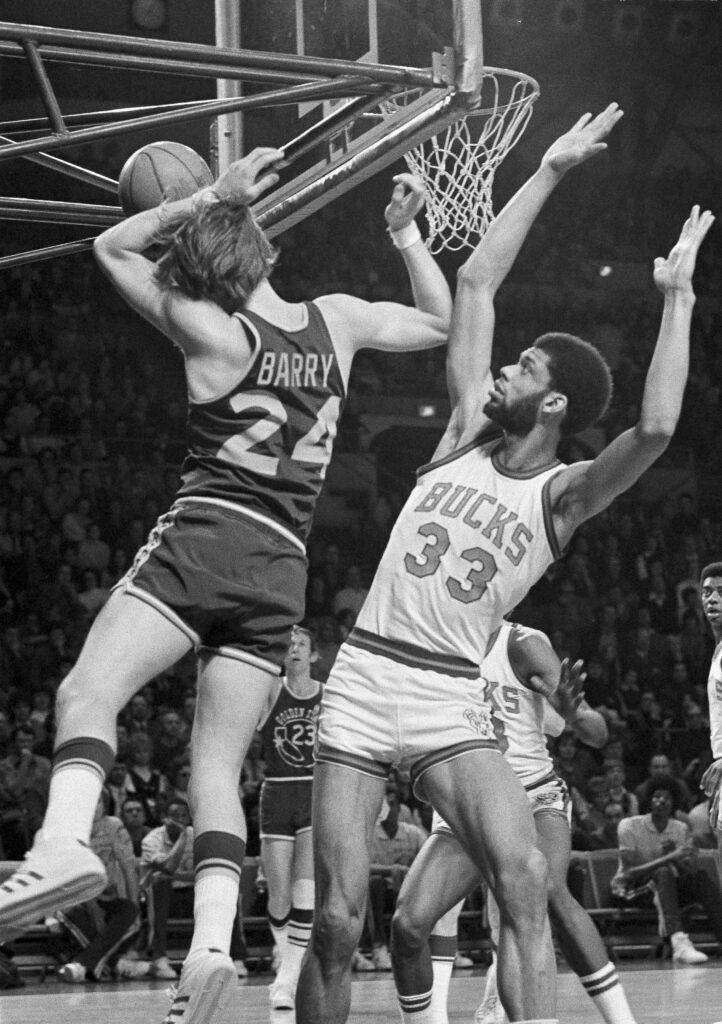 The ball hits the lower supports of the basket as Rick Barry (24) of the Golden State Warriors is cut short by Kareem Abdul-Jabbar (33) of the Milwaukee Bucks in Milwaukee, Wis., April 1, 1973. (AP Photo/Paul Shane)
