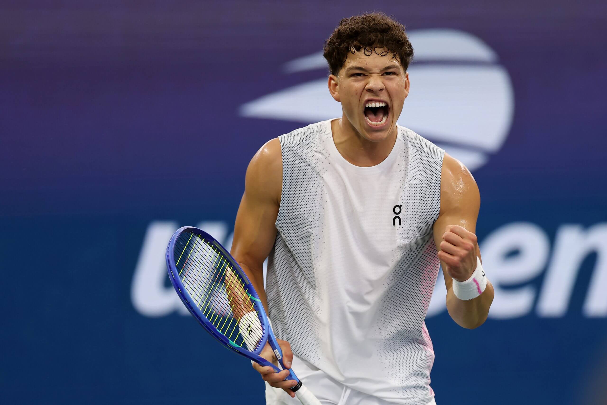 Ben Shelton roars looking on in front of a U.S. Open logo.