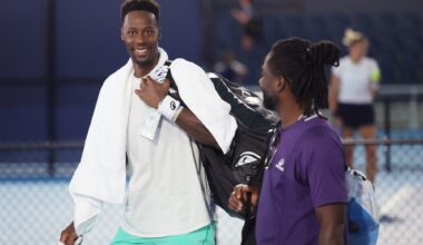 Monfils walking across the court and smiling at the camera with a towel around his neck