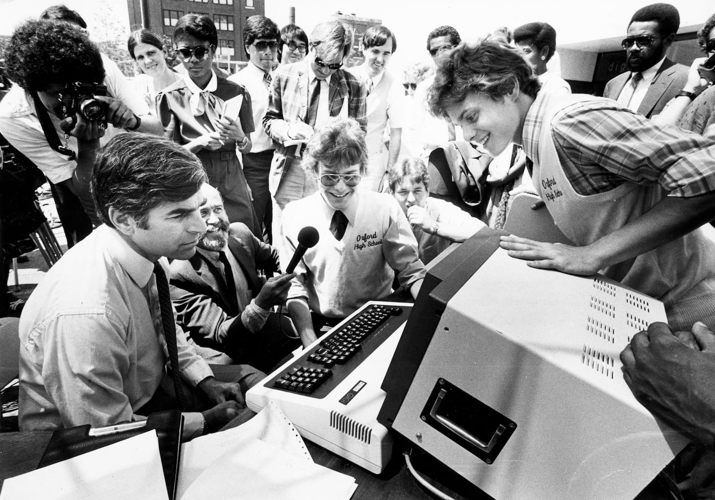 Twins Garry Goodell (leaning over) and Jim Goodwell explained a computer program to Governor Michael Dukakis at a press conference at Digital Equipment Corp. in Roxbury on June 22, 1983.  