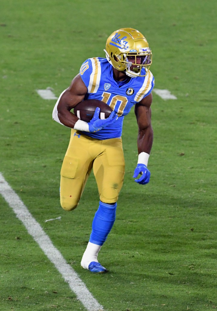 A football player in a blue and gold uniform with the number 10 runs with the ball on a green field.