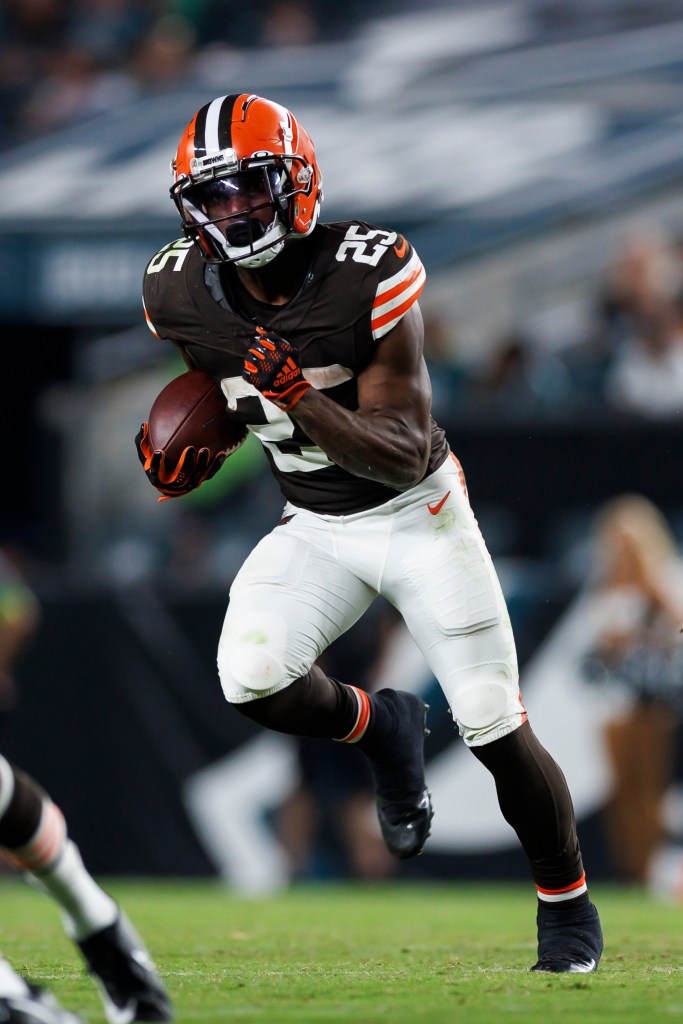 Football player in a brown and orange uniform running with the ball.