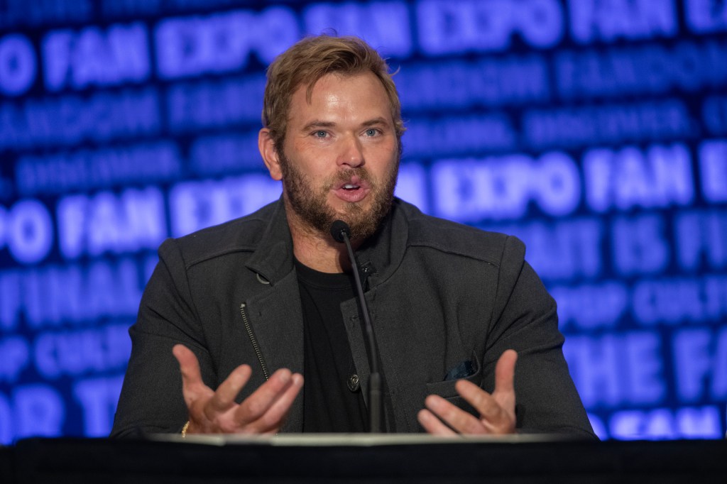 Kellan Lutz speaking into a microphone at Fan Expo Denver.
