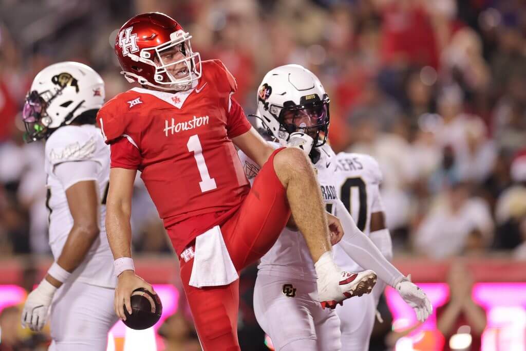 Connor Weigman raises his left leg while holding the football in his left hand