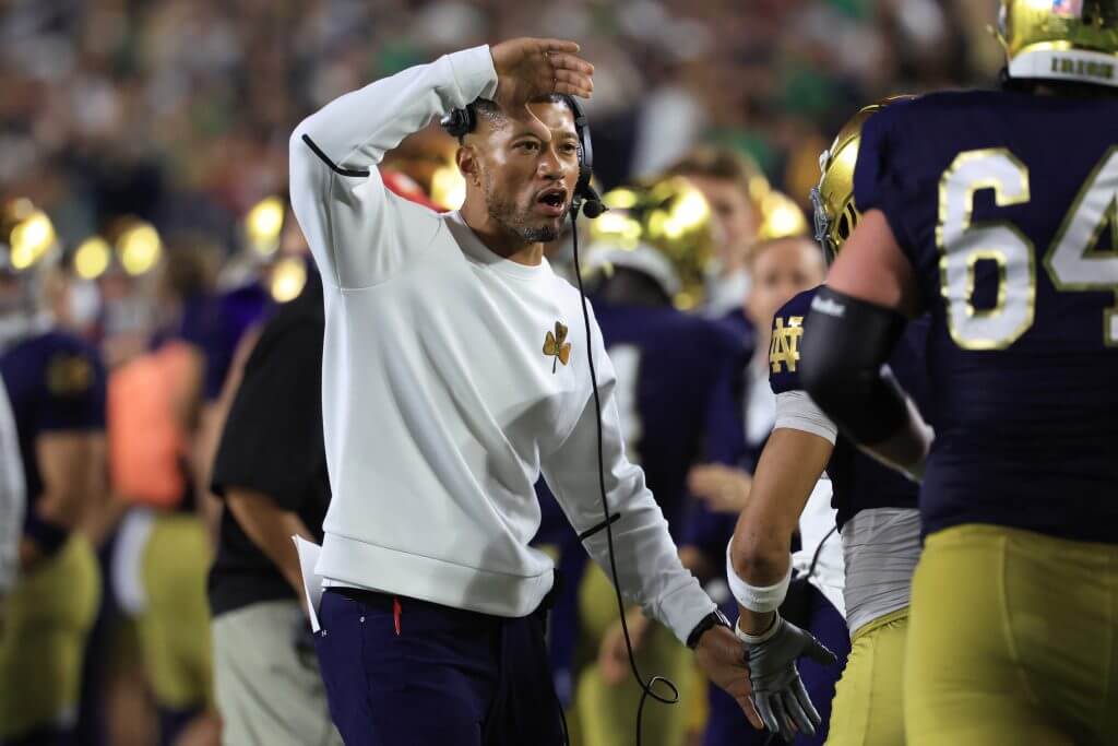 Marcus Freeman raises his left arm to celebrate with a Notre Dame player