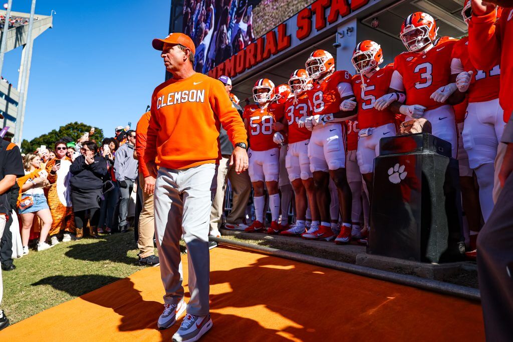 Dabo Swinney looks forward standing in front of Clemson players on the hill at Memorial Stadium