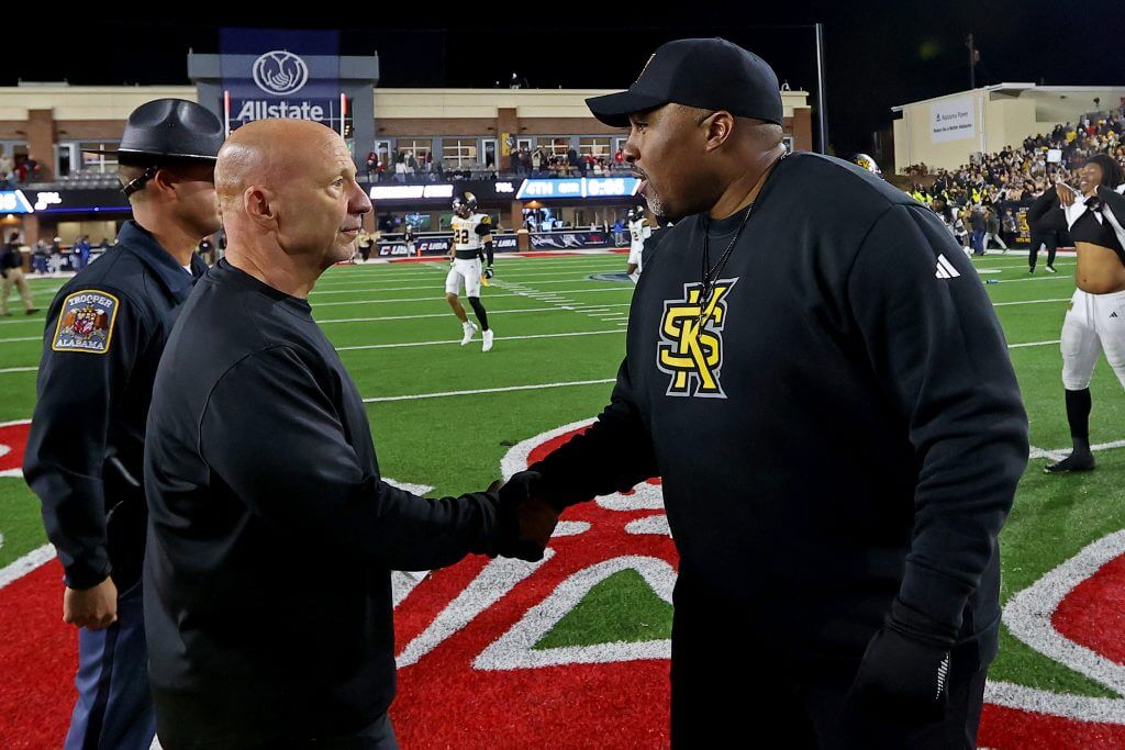Charles Kelly and Jerry Mack shake hands at midfield
