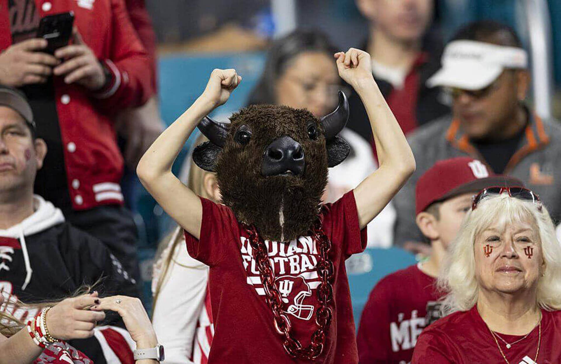 An Indiana fan, wearing a bison mascot head, cheers for their team at the national championship game.