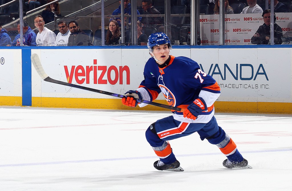 A New York Islanders player #73 skates across the ice with his hockey stick.
