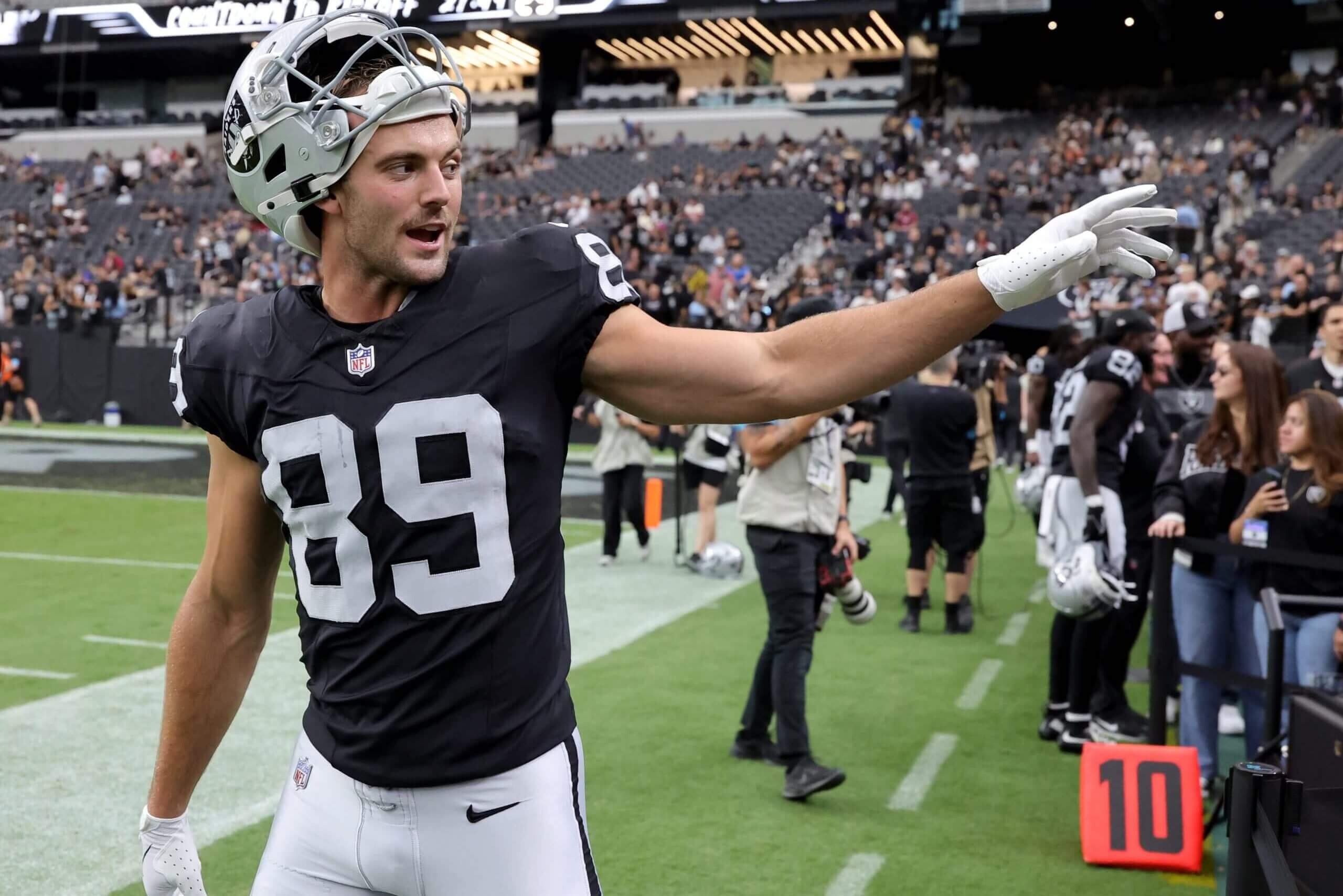 Brock Bowers waves to fans after warming up before a preseason game against the Arizona Cardinals.