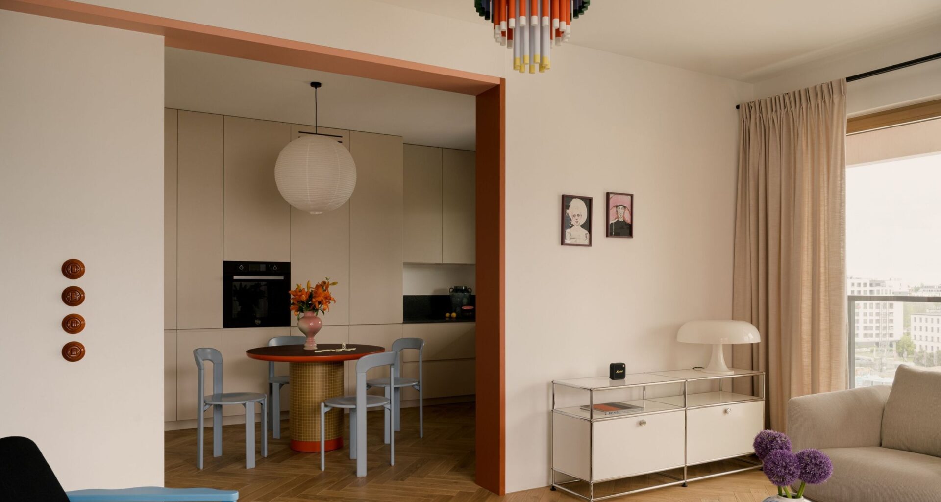 An open-plan living and kitchen space toys with colour and calm &ndash; white walls with bright furniture.