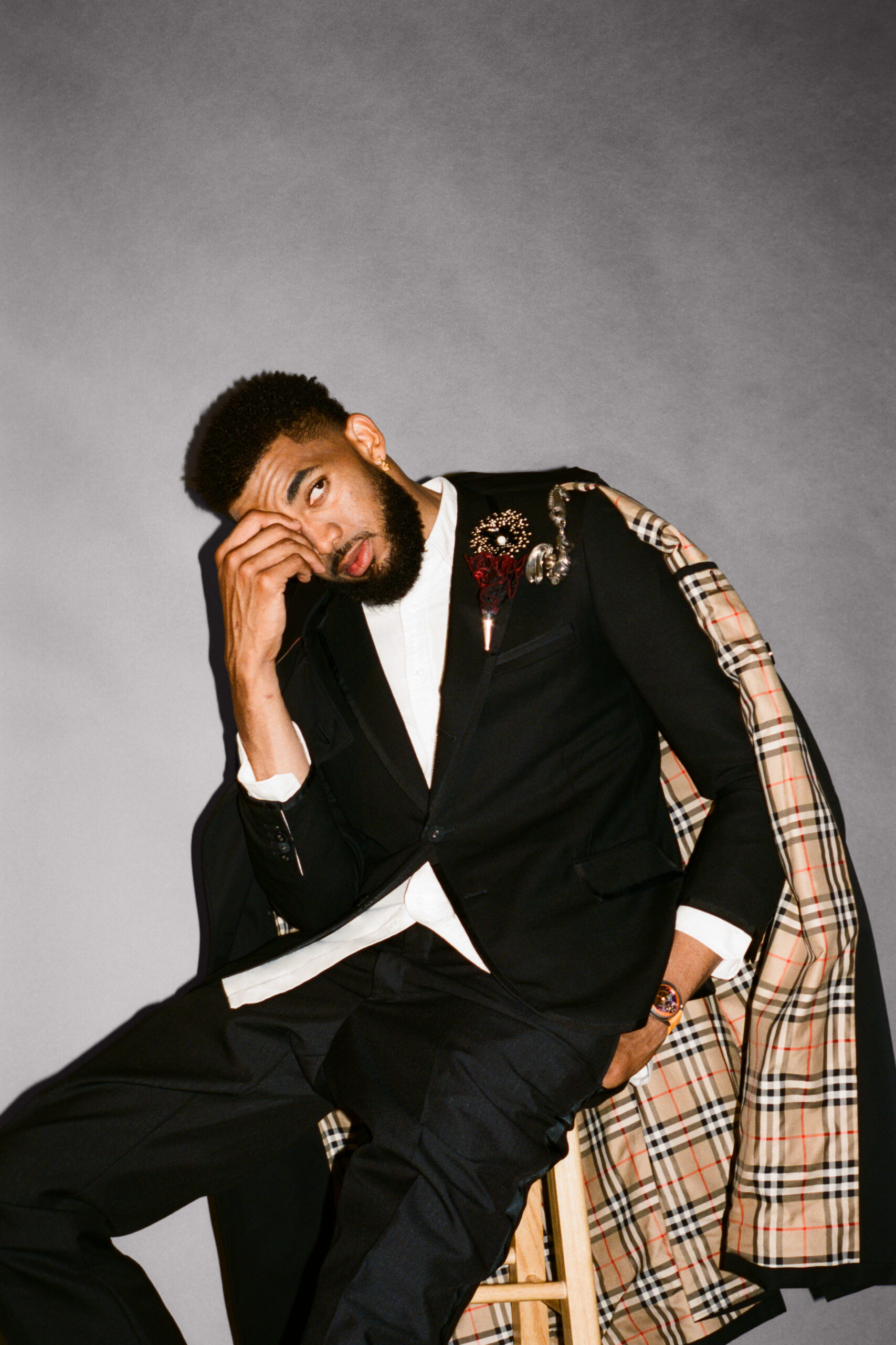 Karl-Anthony Towns sits in a chair wearing a suit with his hand covering his eye.