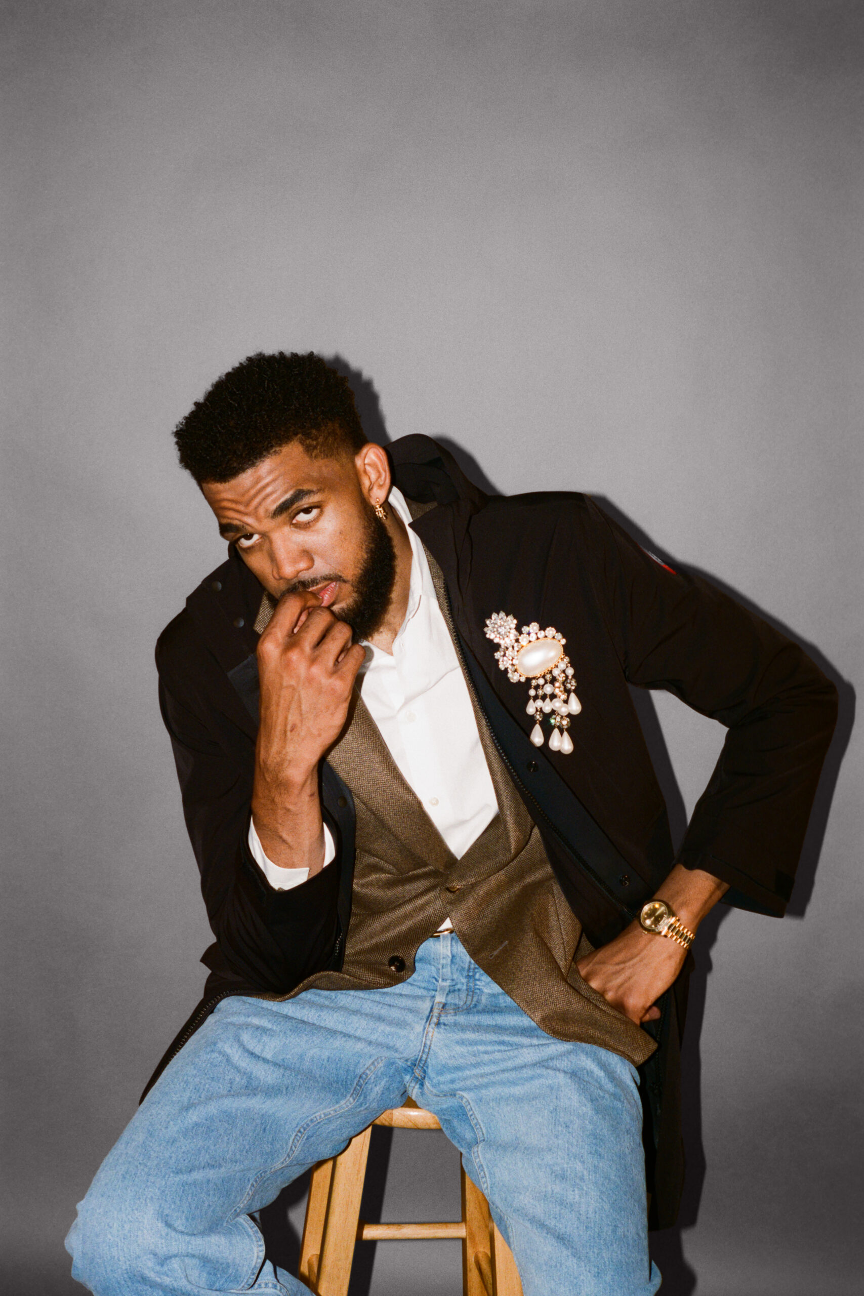 Karl-Anthony Towns sits in a stool, staring sternly into the camera biting his thumb.